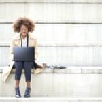 Junge Geschäftsfrau mit Laptop auf einer Treppe