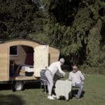 Personen trinken Kaffe auf der Wiese mit dem Caravan "freechilli"